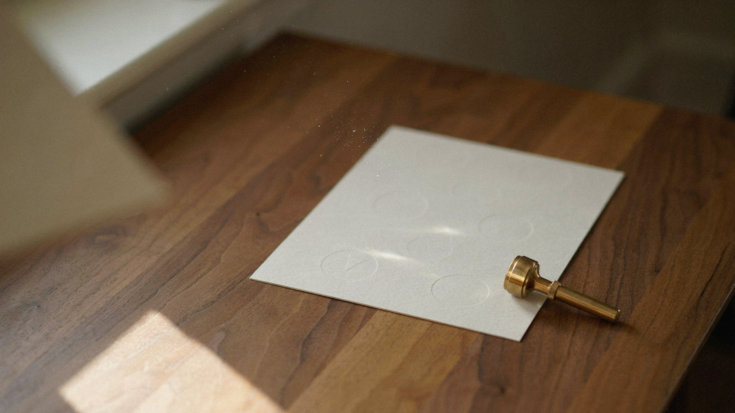Warm ivoorkleurig kaartje met ronde coatingmarkeringen naast een messing loep op walnoothout