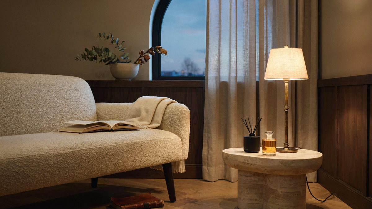 Warme hotelachtige lounge met huisgeurdetails naast een lamp