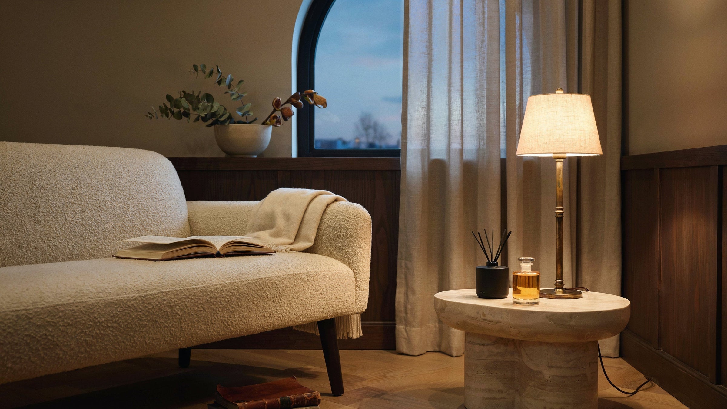 Warme hotelachtige lounge met huisgeurdetails naast een lamp